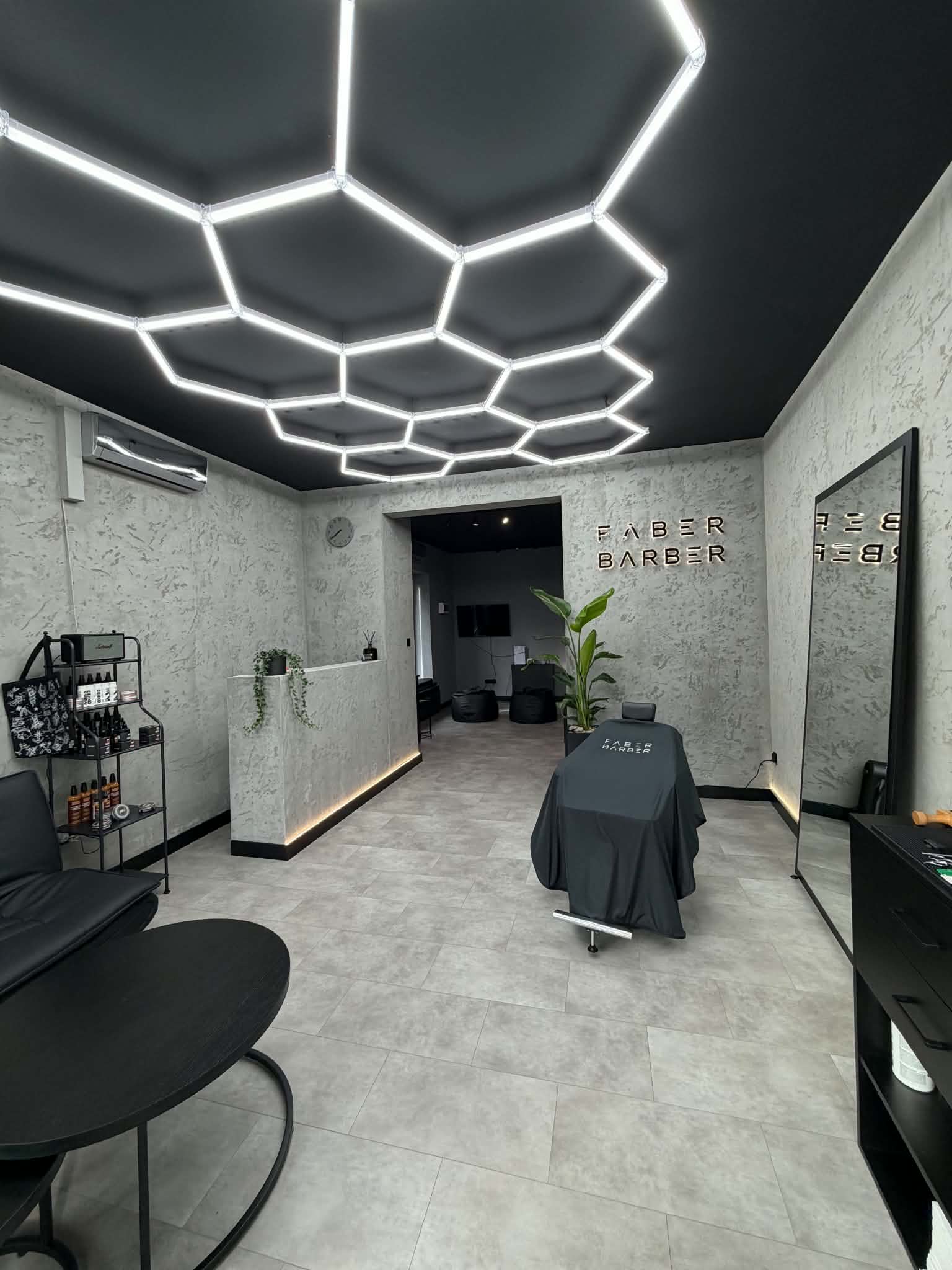Wnętrze salonu FABER BARBER — recepcja, fotel i podświetlany sufit